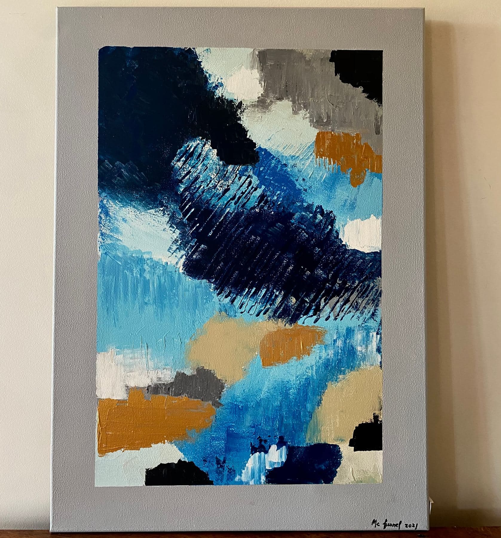 Toile abstraite verticale bleue, blanche, grise et ocre, avec une large bordure peinte visible autour de la composition